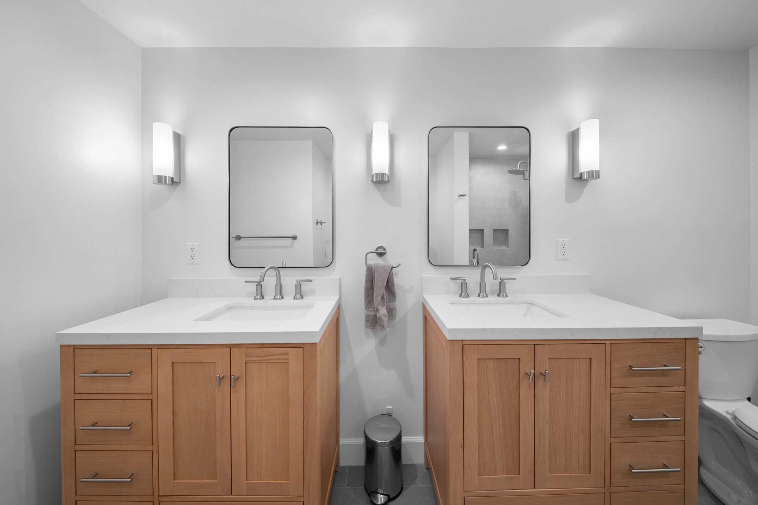 Dual vanity bathroom with natural wood shaker cabinets, white quartz countertops, and brushed nickel fixtures by RnD Builders Inc