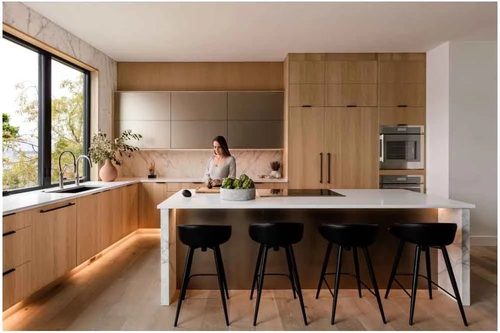 Modern open kitchen with white oak flat-panel cabinets, marble backsplash, and waterfall island by RnD Builders Inc